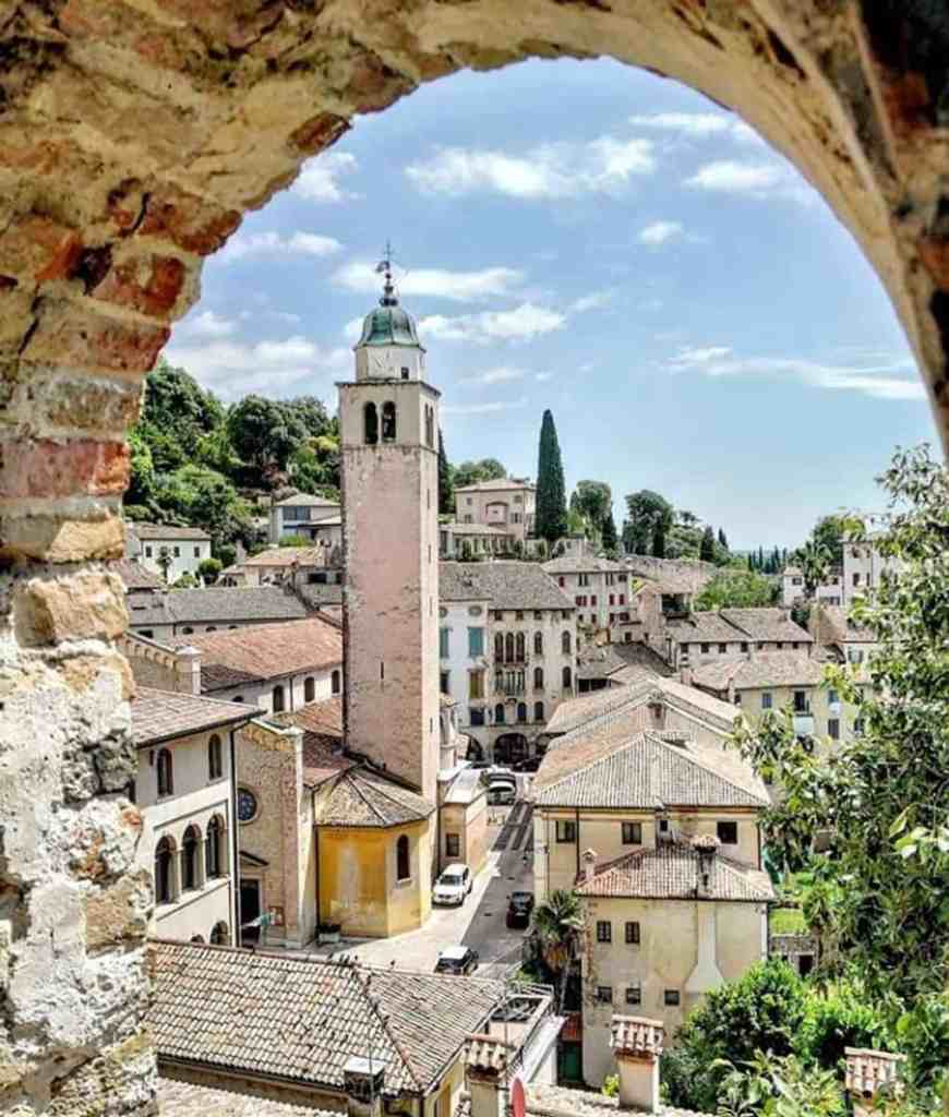Vista panoramica del centro storico di Alano di Piave con torre e case tradizionali.